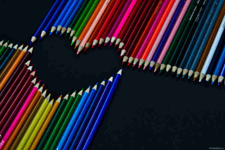 Bút chì nhiều màu xếp thành hình trái tim trên nền màu đen